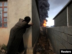 FILE - A woman looks at fire and smoke from oil wells set ablaze by Islamic State militants before the fled the oil-producing region of Qayyara, Iraq, Nov. 4, 2016.