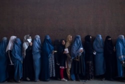 Para perempuan berbaris untuk menerima uang tunai di titik distribusi uang yang diselenggarakan oleh Program Pangan Dunia, di Kabul, Afghanistan, Sabtu, 20 November 2021. (Foto: AP)