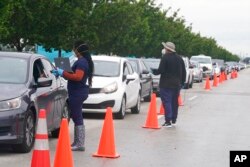 Employees of Nomi Health check in a long line of people for COVID-19 tests, in North Miami, Fla., Dec. 21, 2021.