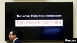 FILE - Treasury Secretary Steven Mnuchin walks past a display of the U.S. national debt on Capitol Hill in Washington, Feb. 6, 2018. On Tuesday, the Treasury Department's daily statement showed the national debt topped $22 trillion for the first time.