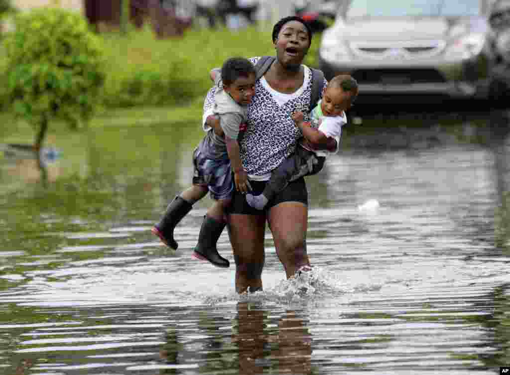 A woman named Terrian Jones reacts when she feels something moving in the water at her feet as she carries Drew and Chance Furlough to their mother on Belfast Street in New Orleans, Louisiana, during flooding from a heavy storm in the Gulf Mexico, July 10, 2019.