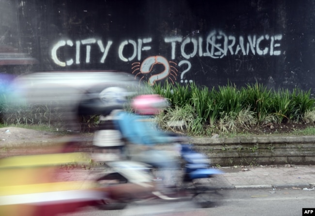 Seorang pengendara melewati grafiti yang menyerukan toleransi di Yogyakarta. (Foto: AFP)
