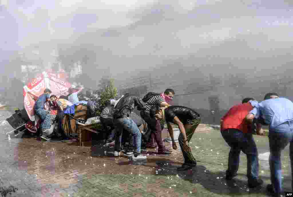 Left-wing militants protect themselves as Turkish anti-riot police fires water cannon to disperse a demonstration in Istanbul&#39;s Gazi district. Tensions across the country are high, with police routinely using water cannon to disperse nightly protests in Istanbul and other cities denouncing IS and the government&#39;s policies on Syria.