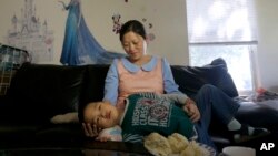 Liu Xiaodong, istri pembangkang China Zhao Changqing, bersama anak mereka Yaokun Zhao saat diwawancara di Hayward, California (20/7). (AP/Jeff Chiu)