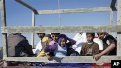Children sit in the back of an open-air truck as they flee Brega during an exchange of fire with pro-Gadhafi forces, in Libya, April 4, 2011