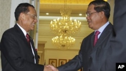 Prime Minister Hun Sen, right, shakes hands with Thai Deputy Prime Minister Trairong Suwankiri, left, in the Peace Palace in Phnom Penh.