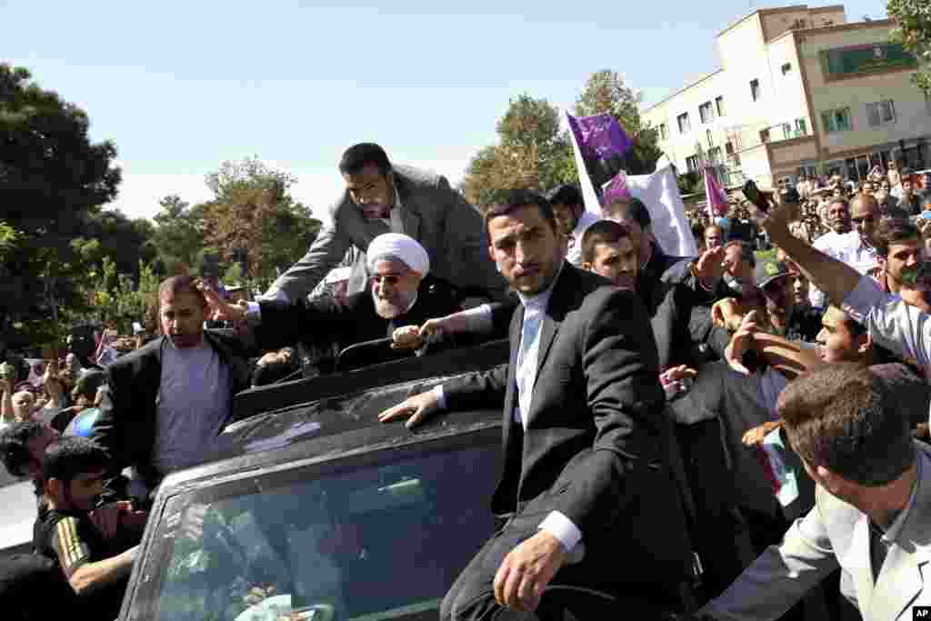 Iranian President Hassan Rouhani, center, waves to supporters upon his arrival from the U.S. near the Mehrabad airport in Tehran.