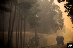 A police water cannon sprays water into a forest near Treuenbrietzen, south of Berlin, Aug. 24, 2018 after a trees on an area of several hundred soccer fields caught fire.