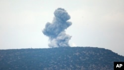 A plume of smoke from an air bombardment rises from an impact inside Syria as seen from the Hatay province, Turkey, near the border Jan. 24, 2018.