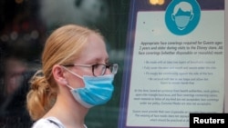 A woman wears a mask against the coronavirus disease (COVID-19), following the CDC recommendation that fully vaccinated Americans wear masks as the highly transmissible Delta variant has led to a surge in infections, as she enters the Disney Store in Time