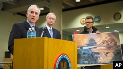 An aide to Metro General Manager Paul Wiedefeld (l) holds up a photo of a track damaged by fire as Wiedefeld speaks during a news conference to announce that the DC Metrorail service will be shut down for a full day, at the Washington Metropolitan Area Tr