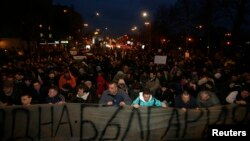 Protestors kneel as Bulgarian national anthem is played, as they block a main boulevard during demonstration against high electricity prices in Sofia, February 20, 2013.