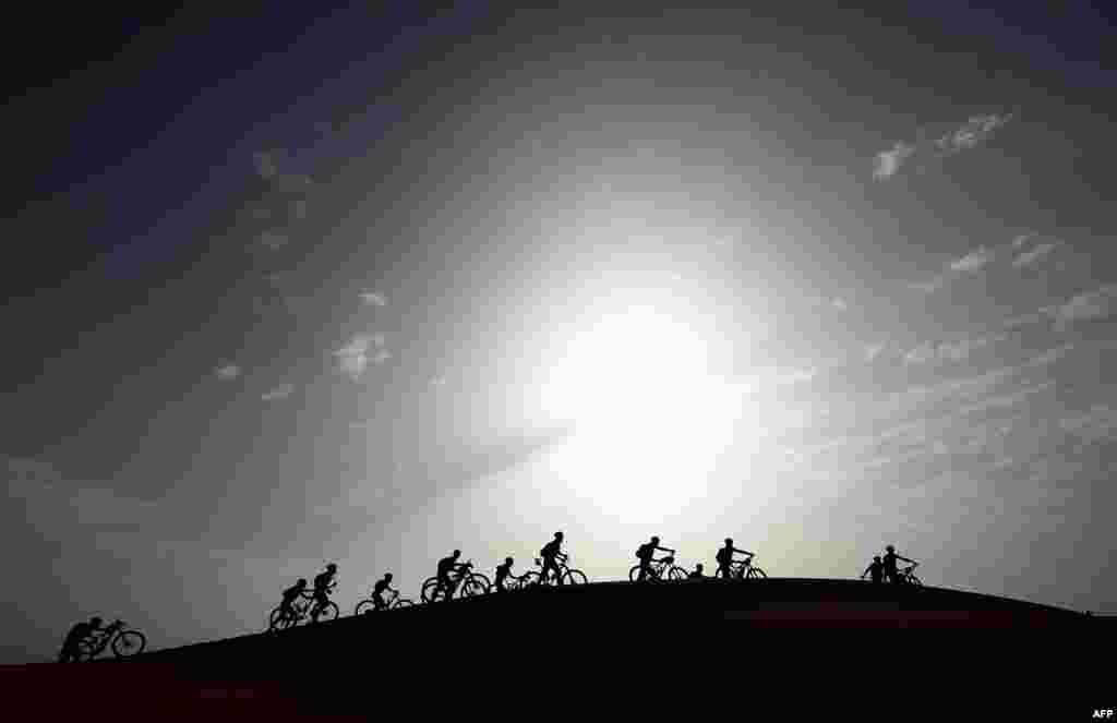 Competitors push their bikes up a sand dune during Stage 5 of the 13th edition of the Titan Desert 2018 mountain biking race around Merzouga in Morocco.