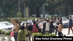 Families gather outside the health department in the southern city of Guangzhou to petition against fines for couples who had more than one child before the country ended its one-child policy.