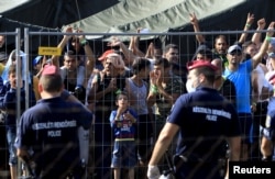 Syrian migrants shout slogans at a refugee camp in Roszke, Hungary, Aug. 28, 2015.