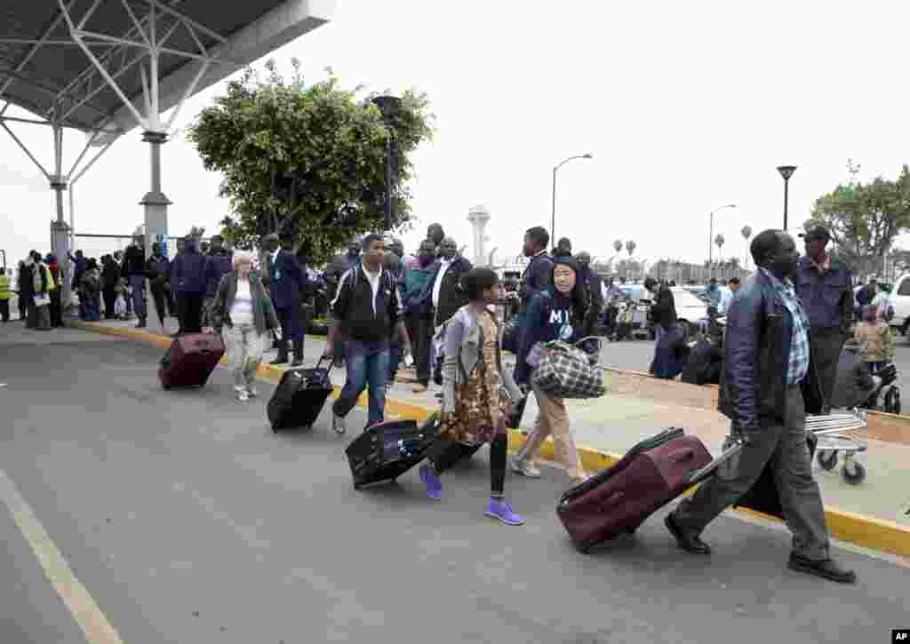 International passengers walk from the airport to be taken to hotels after a fire forced the closure of Jomo Kenyatta International Airport, Nairobi, August 7, 2013.