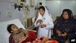 A Pakistani nurse and unidentified relatives of Shumaila Kanwal, bottom, the widow of a Pakistani man allegedly shot and killed by a U.S. official, stand beside her at a local hospital in Faisalabad, Pakistan, after she ate rat poison, February 6, 2011