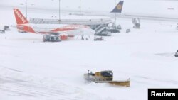 A snowplow removes snow next to EasyJet and Lufhansa aircraft during a temporary closure at Cointrin airport in Geneva, Switzerland, March 1, 2018.