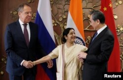 Russian Foreign Minister Sergei Lavrov (L) Indian Foreign Minister Sushma Swaraj (C) and Chinese Foreign Minister Wang Yi shake hands before the start of their meeting in New Delhi, India, Dec. 11, 2017.