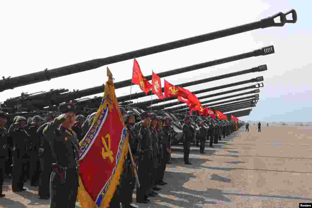 북한 인민군 창건 85주년 경축 군종합동타격시위에서 군인들이 포를 배경으로 경례하고 있다.