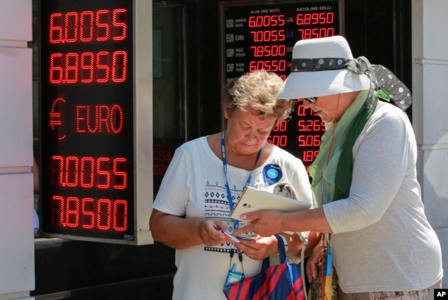 Tourists count their Turkish liras after exchanging foreign currency at a exchange shop in Istanbul, Aug. 13, 2018.