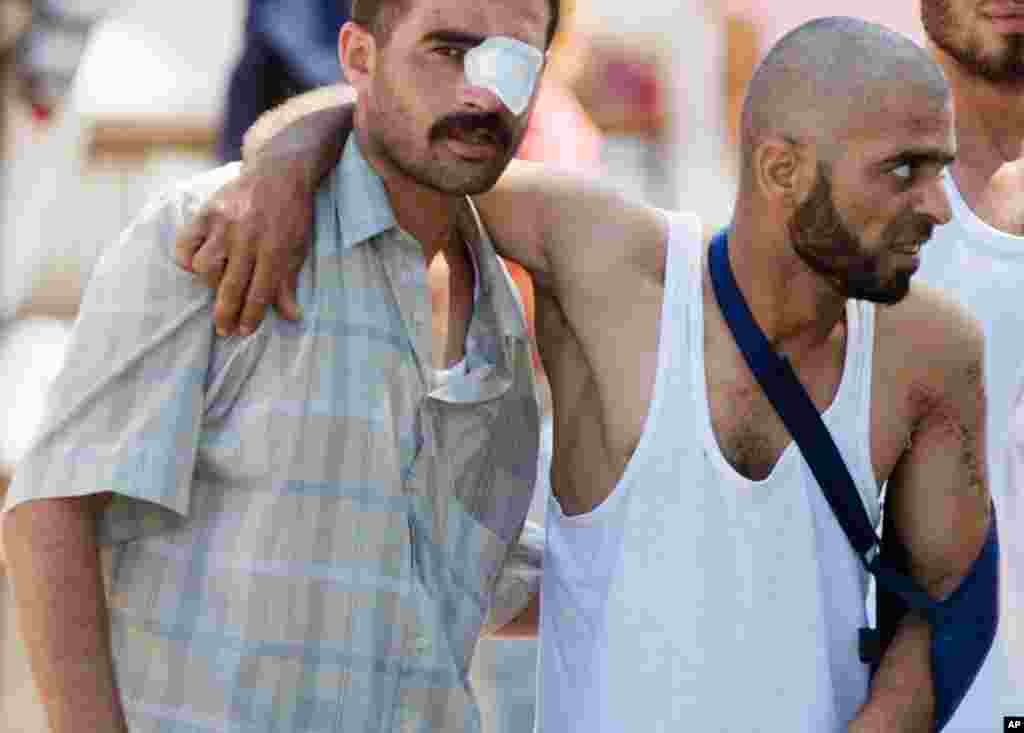 June 22: Wounded Syrian refugees help each other as they head toward an ambulance in the Turkish town of Yayladagi. (AP Photo/Burhan Ozbilici)