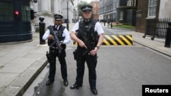 Armed police officers pose for the media in Downing Street, central London, Aug. 29, 2014. 