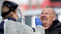 In this April 17, 2020, file photo, a man reacts as a medical staffer tests shoppers who volunteered at a pop-up community COVID-19 testing station at a supermarket carpark in Christchurch, New Zealand. (AP Photo/Mark Baker,File)