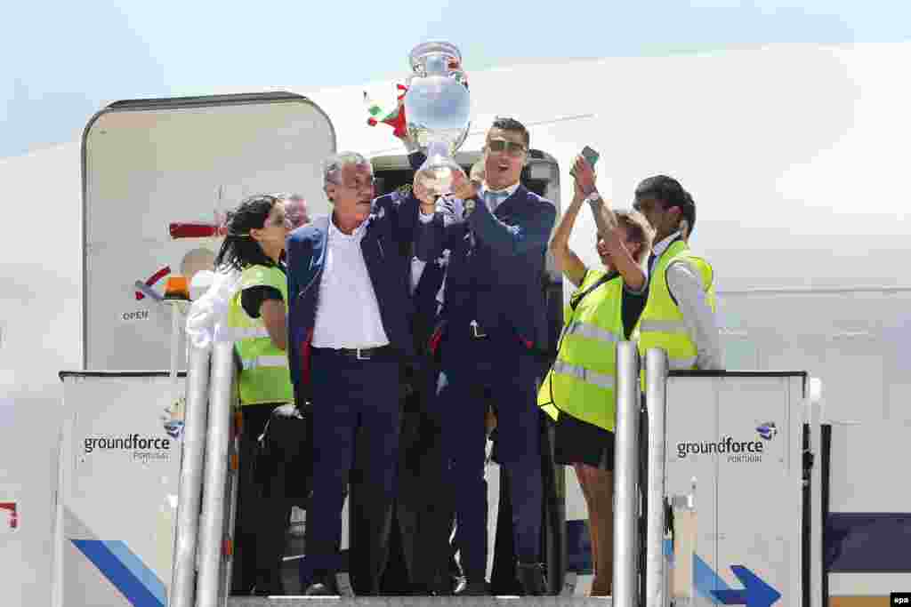 L’entraîneur du Portugal Fernando Santos, à gauche, et le capitaine Cristiano Ronaldo, à droite, sortent de l’avion brandissant le trophée de l’Euro 2016, à l'aéroport Humberto Delgado à Lisbonne, Portugal, 11 juillet 2016. epa / MARIO CRUZ