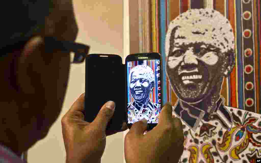 Khách tham quan chụp ảnh trong ngày khai mạc triển lãm quốc tế 95 bức áp phích tôn vinh 95 năm cuộc đời của ông Nelson Mandela tại Đại học Pretoria, Nam Phi, 17 tháng 7, 2013.