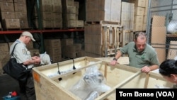 U.S. Fish and Wildlife Service Special Agent In Charge Eric Marek (center right) and Supervisory Wildlife Inspector John Goldman (left) examine a shipment of African hunting trophies at a customs bonded warehouse near Seattle-Tacoma International Airport.