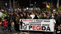 Les protestataires tiennent une banderolle sur laquelle on peut lire : " Sans violence et unis contre la guerre des relions sur le sol allemand" - Pegida" pendant un meeting during à Dresden, l'est de l'Allemagne, le 2 novembre, 2015. (AP Photo/Jens Meyer)