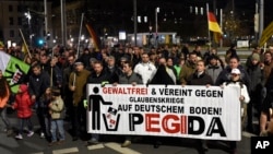 FILE - Protesters hold a banner reading "Without violence and united against religious wars on German soil - Pegida" during a rally in Dresden, eastern Germany, Nov. 2, 2015.