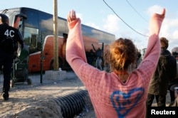 FILE - A volunteer waves to migrant minors in a bus during their transfer by French authorities to reception centers across the country at the end of the dismantlement of the camp called "the Jungle" in Calais, France, Nov. 2, 2016.