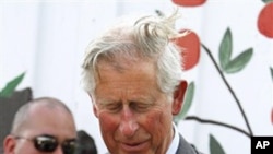 Britain's Prince Charles looks at flowers he received during a visit to Common Good City Farm in Washington, on Tuesday, May 3, 2011
