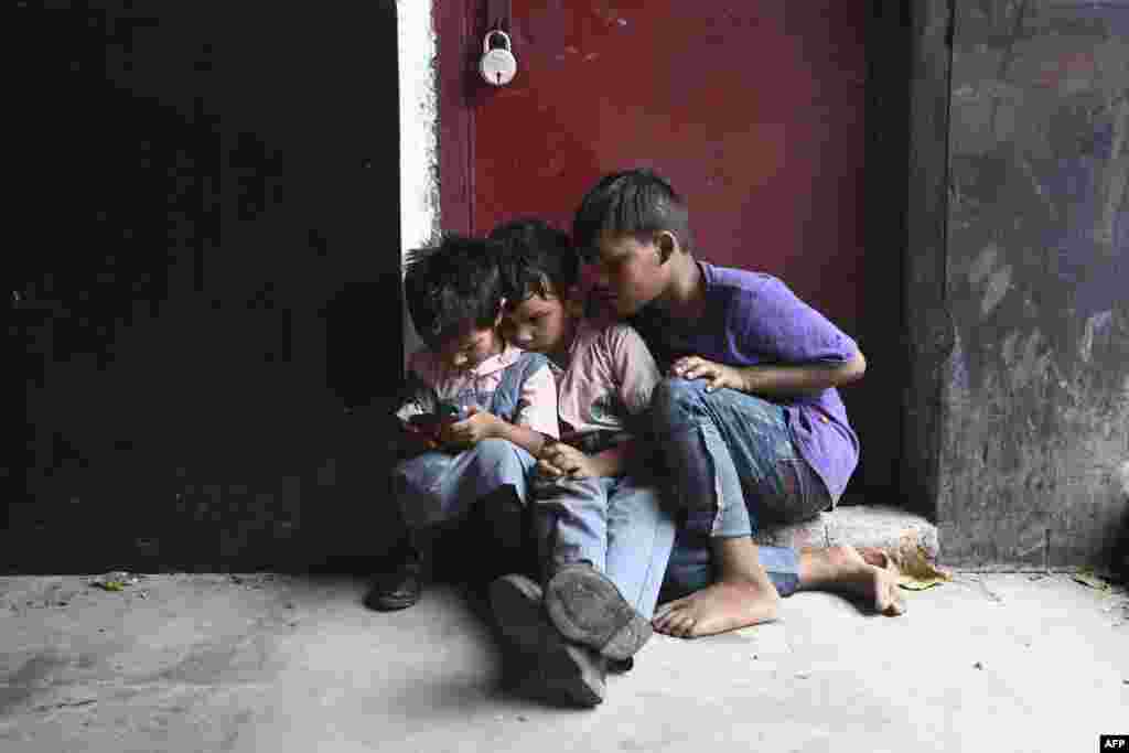 Children play on a cell phone at a market in New Delhi, India.