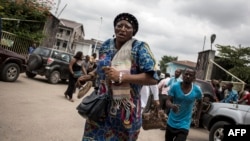 A Congolese woman runs for cover after police fired warning shots to disperse a crowd at the end of a Catholic service that commemorates the victims of a crackdown on last month's march on Jan. 12, 2018 in Kinshasa.