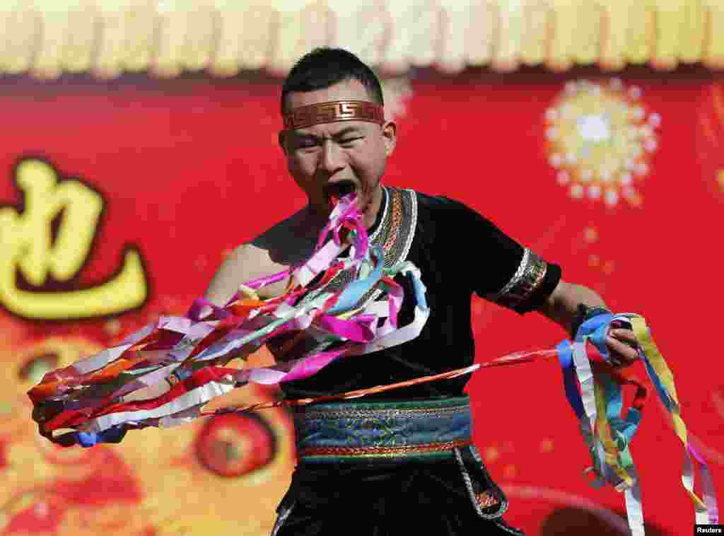 A man pulls ribbons from his mouth as he performs a feat of his strength during the opening of the temple fair for Chinese New Year celebrations at Ditan Park, also known as the Temple of Earth, in Beijing, China.