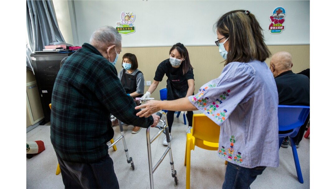 Pemilik salon Cass Ng membantu seorang lansia sebelum memberinya pelayanan pedikur di pusat komunitas lansia di Hong Kong sebagai bagian dari inisiatif amal, 8 November 2021. (Foto: AFP/Isaac Lawrence)