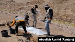 Employees of Iraq's Ministry of Health collect the remains of bodies of people who, according to Iraqi officials, were killed by Islamic state militants, during the exhumation of a mass grave in Mosul, Iraq June 13, 2021.