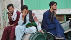 FILE - Afghan men sit in a courtyard inside a Shiite mosque in Kandahar on Oct. 15, 2021, after a suicide bomb attack during Friday prayers that killed more than 30 people.