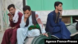 FILE - Afghan men sit in a courtyard inside a Shiite mosque in Kandahar on Oct. 15, 2021, after a suicide bomb attack during Friday prayers that killed more than 30 people.