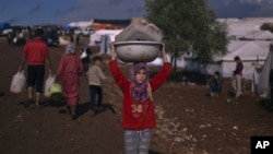 A Syrian girl who fled with her family from the violence in their village, carries a plastic container over her head as she walks to fill it with water at a displaced camp, in the Syrian village of Atma, near the Turkish border with Syria, November 10, 20