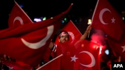 FILE - Government supporters wave Turkish flags and shout slogans during a protest in Taksim Square, Istanbul, July 19, 2016.