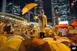 FILE - In this Oct. 9, 2014, file photo, a protester holds an umbrella during a performance on a main road in the occupied areas outside government headquarters in Hong Kong's Admiralty. (AP Photo/Kin Cheung, File)