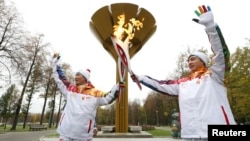 Student Anatoly Chentuloev (R) and journalist Yeon Kyu-sun pose for a picture during the the Sochi 2014 Winter Olympic torch relay in Moscow Oct. 8, 2013.