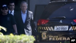 FILE - Jose Dirceu, former presidential chief of staff, center, is accompanied by federal police agents to a car at a police station in Brasilia, Aug. 4, 2015.