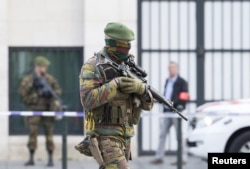 FILE - A Belgian special forces police officer and soldiers secure the zone outside a courthouse while Brussels attacks suspects Mohamed Abrini and Osama Krayem appear before a judge in Brussels, Belgium, April 14, 2016.