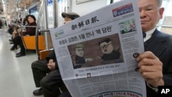 A passenger reads a newspaper with headline of a planned summit meeting between North Korean leader Kim Jong Un and U.S. President Donald Trump, left, at subway train in Seoul, South Korea, March 10, 2018. 