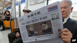 A passenger reads a newspaper with headline of a planned summit meeting between North Korean leader Kim Jong Un and U.S. President Donald Trump, left, at subway train in Seoul, South Korea, March 10, 2018. The White House tried to swat away criticism Friday that the U.S. is getting nothing in exchange for agreeing to a historic face-to-face summit between President Donald Trump and North Korean leader Kim Jong Un. 